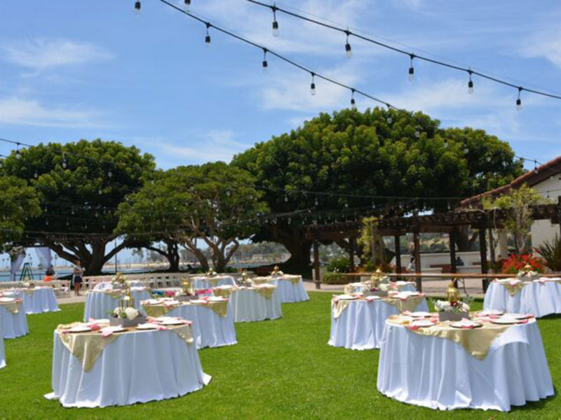 Outdoor tables set on a lawn with string lights.