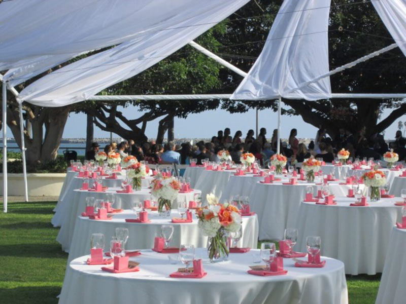 Decorated round tables under white canopy outdoors.